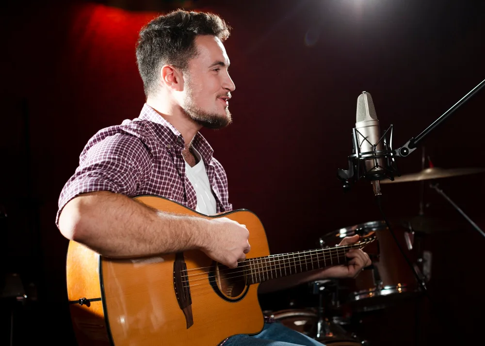 Homme chantant avec sa guitare devant un micro